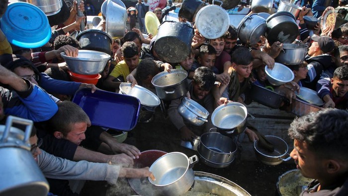 Palestinians gather to receive food cooked by a charity kitchen, amid a hunger crisis, as the Israel-Gaza conflict continues, in Khan Younis in the southern Gaza Strip, November 19, 2024. REUTERS/Hatem Khaled