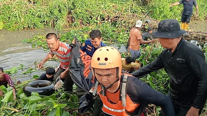 Petugas saat mengevakuasi jasad bocah 6 tahun yang terbawa drainase perumahan