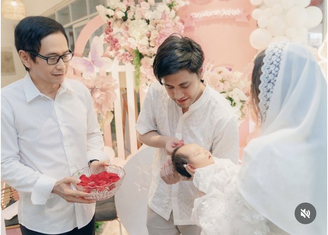 Kevin dan Vicy kompak menjalani satu per satu rangkaian acara. Dalam foto terlihat Kevin yang sedang menggunting rambut sang anak, sementara Vicy yang menggendong baby Kimova. Foto: Instagram/@vicymelanie