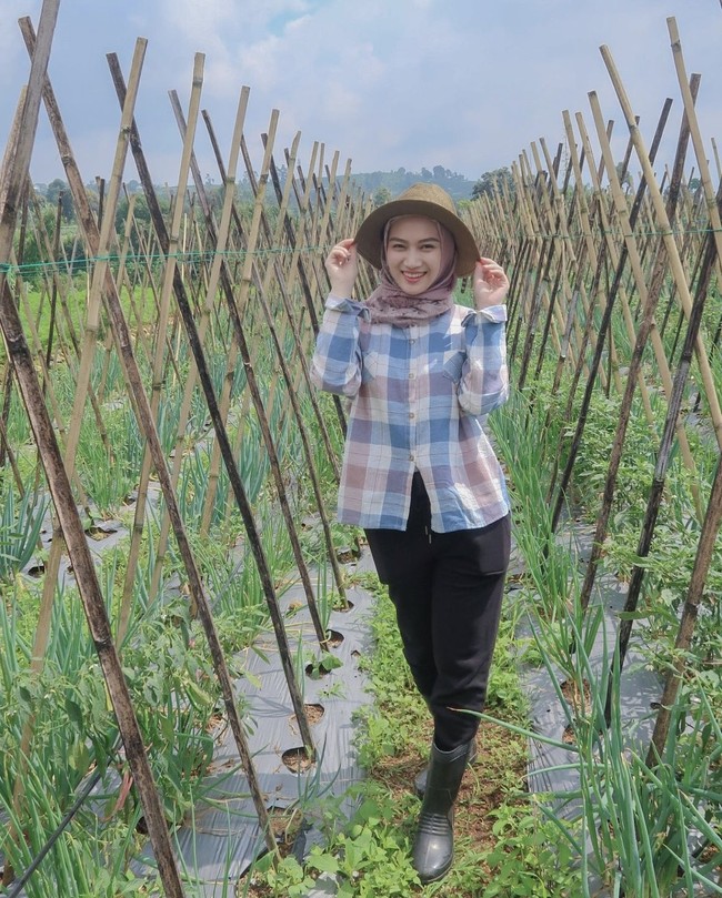Dalam foto lain terlihat Melody mengenakan kemeja kotak-kotak dipadukan dengan hijab berwarna coklat dan celana panjang hitam. Berpose di tengah-tengah lahan pertanian, Melody tampak memamerkan senyum manisnya. Foto: Instagram/@melodylaksani92