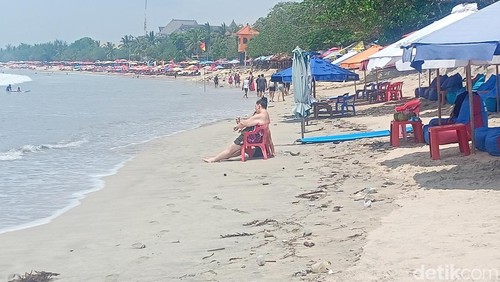 Kondisi ombak pantai Kuta hampir menerjang turis yang sedang duduk santai di bibir pantai, Rabu (20/11/2024). 
(Agus Eka/detikBali)