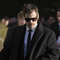 Harry Styles yang juga berbusana hitam-hitam tampak selalu menundukkan kepalanya saat hadir di pemakaman. Foto: AP/Andrew Matthews