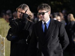 Niall Horan ditemani kekasihnya, Amelia Woolley, berbusana hitam-hitam. Dia mengenakan mantel di atas kemeja putih dan dasi hitam. Raut kesedihan juga terpampang jelas di wajahnya. Foto: AP/Andrew Matthews