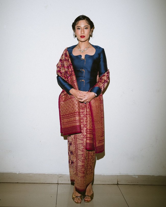 Dian Sastrowardoyo mengenakan kebaya modifikasi berpotongan struktural dengan garis leher unik. Kebaya biru gelap metalik dipadankan dengan kain songket. Kalung emas berhias berhias permata dan anting melengkapi keanggunan busananya. Foto: Instagram