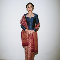 Dian Sastrowardoyo mengenakan kebaya modifikasi berpotongan struktural dengan garis leher unik. Kebaya biru gelap metalik dipadankan dengan kain songket. Kalung emas berhias berhias permata dan anting melengkapi keanggunan busananya. Foto: Instagram