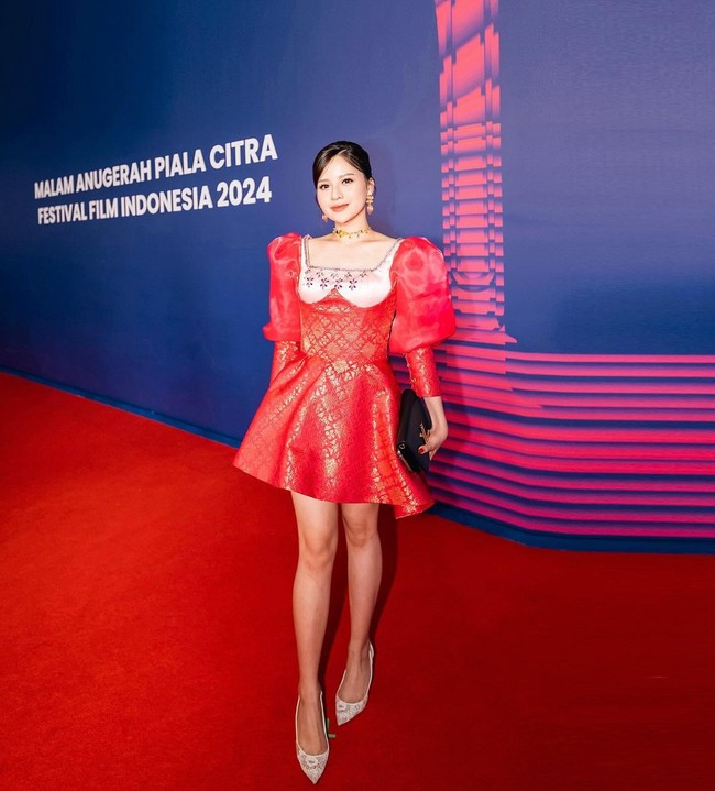 Penyanyi Anggi Marito tampil dengan busana cocktail merah bergaya girlie. Gaun mini tersebut terbuat dari bahan songket yang dipercantik detail puff di lengan. Foto: Instagram