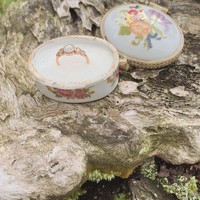 Cincin yang diberikan tampak berwarna emas dengan batu berwarna putih yang menghiasi bagian tengahnya. Di salah satu unggahannya terlihat cincin tersebut diletakkan di sebuah tempat porselen unik bergambar bunga. Foto: Instagram/@cakecaine