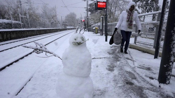 A woman walks past a snowman on the platform of the Louveciennes train station, west of Paris, Thursday, Nov. 21, 2024. (AP Photo/Michel Euler)