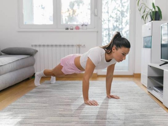 Beautiful young woman in sports clothing doing push-ups at home