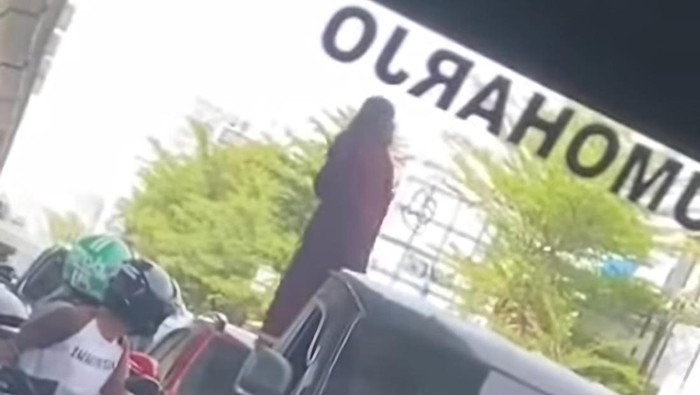 Tangkapan layar wanita naik ke atap mobil pengendara di Jalan AP Pettarani Makassar.