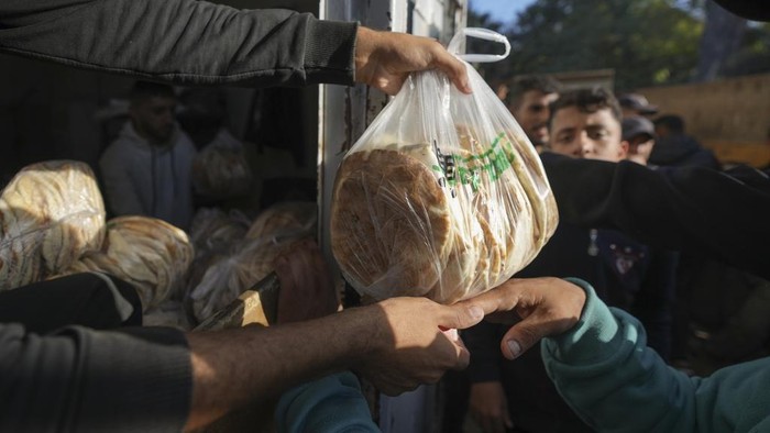 A crowd gathers in front of a bakery to get a share of bread in Deir al-Balah, Gaza Strip, Thursday Nov. 21, 2024. Some bakeries in the Gaza Strip have reopened Thursday morning after shuttering for several days due to a flour shortage and lack of food aid.(AP Photo/Abdel Kareem Hana)
