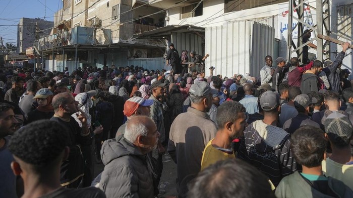 A crowd gathers in front of a bakery to get a share of bread in Deir al-Balah, Gaza Strip, Thursday Nov. 21, 2024. Some bakeries in the Gaza Strip have reopened Thursday morning after shuttering for several days due to a flour shortage and lack of food aid.(AP Photo/Abdel Kareem Hana)