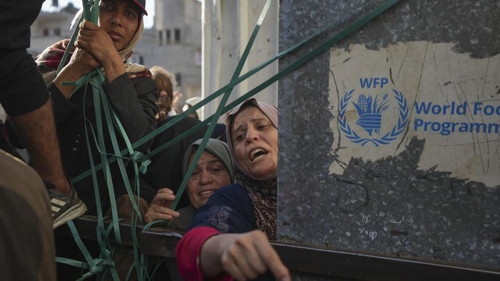 A crowd gathers in front of a bakery to get a share of bread in Deir al-Balah, Gaza Strip, Thursday Nov. 21, 2024. Some bakeries in the Gaza Strip have reopened Thursday morning after shuttering for several days due to a flour shortage and lack of food aid.(AP Photo/Abdel Kareem Hana)