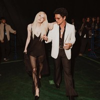 Kehadiran Bruno Mars tentu mengundang perhatian. Penyanyi asal Amerika Serikat tersebut terlihat elegan mengenakan setelan hitam yang dipadukan blazer putih. Gaya Bruno Mars kompak dengan Rose yang memakai mini hitam transparan.   Foto: Internet