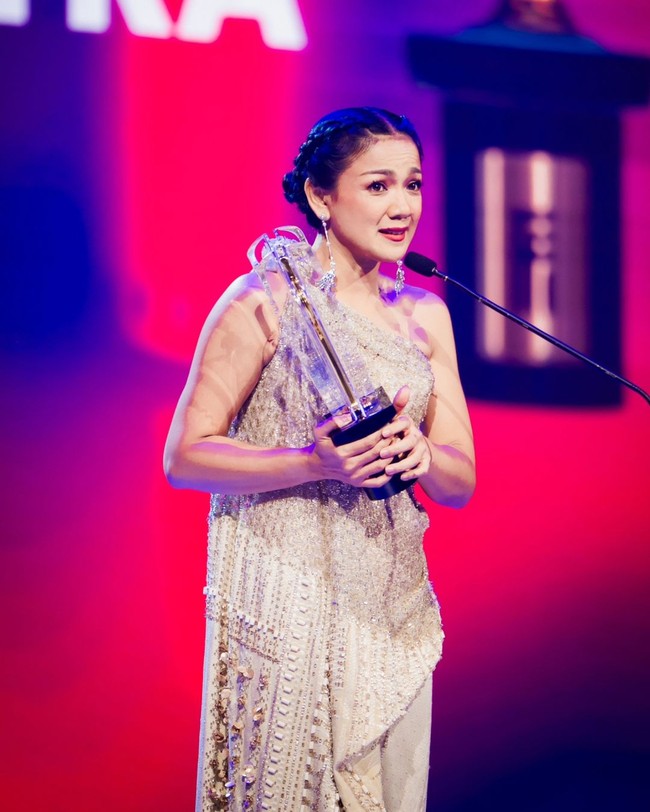 Wanita 44 tahun ini melengkapi busananya dengan anting rantai panjang dari koleksi Epa Jewel. Bibirnya dipulas lipstik merah menambah kesan glamor. Foto: Instagram/@hagaipakan @agrasuseno