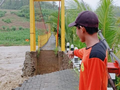 Badan jalan dekat jembatan Desa Kaliguwo-Kalidadap di Kabupaten Wonosobo longsor diterjang banjir Sungai Luk Ulo, Minggu (24/11/2024).