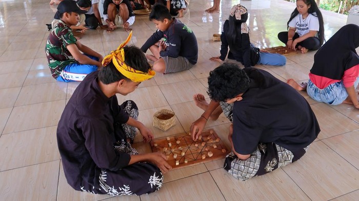 Anak-anak bermain permainan tradisional pateng dudu di Kampung Baca Taman Rimba (Batara) Banyuwangi, Jawa Timur, Minggu (24/11/2024). Kegiatan edukasi yang diisi dengan berbagai permainan tradisional tersebut dalam rangka melestarikan permainan tradisional dan mengasah ketangkasan serta meningkatkan interaksi pergaulan antar anak sehingga diharapkan dapat mengurangi penggunaan gawai yang populer dikalangan anak-anak. ANTARA FOTO/Budi Candra Setya/agr *** Local Caption ***