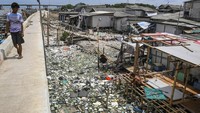 Warga berjalan di tanggul laut Kampung Dadap yang dipenuhi sampah di Kosambi, Kabupaten Tangerang, Banten, Minggu (24/11/2024).