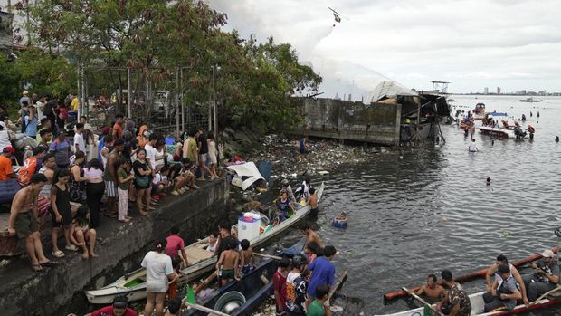 Residents evacuate to safer grounds as fire fighters try to control the fire at a slum area that left about 2,000 families homeless on Sunday, Nov. 24, 2024 in Manila, Philippines. (AP Photo/Aaron Favila)