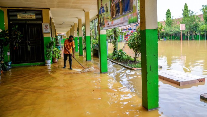 Penjaga sekolah memeriksa lorong sekolah yang terdampak banjir di SMPN 1 Bojongsoang, Kabupaten Bandung, Jawa Barat, Minggu (24/11/2024). Penjaga sekolah mengungkapkan sejak Jumat (22/11/2024) sekolah tersebut terendam banjir akibat intensitas hujan yang tinggi dan luapan Sungai Citarum dan fasilitas sekolah tidak dapat digunakan karena debit air yang masih tinggi. ANTARA FOTO/Raisan Al Farisi/agr