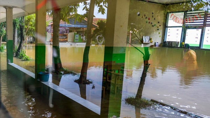 Penjaga sekolah memeriksa lorong sekolah yang terdampak banjir di SMPN 1 Bojongsoang, Kabupaten Bandung, Jawa Barat, Minggu (24/11/2024). Penjaga sekolah mengungkapkan sejak Jumat (22/11/2024) sekolah tersebut terendam banjir akibat intensitas hujan yang tinggi dan luapan Sungai Citarum dan fasilitas sekolah tidak dapat digunakan karena debit air yang masih tinggi. ANTARA FOTO/Raisan Al Farisi/agr