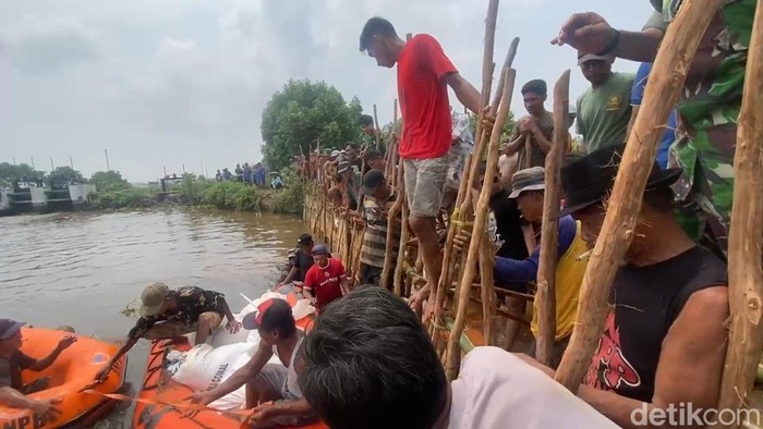 Warga menambal tanggul yang jebol