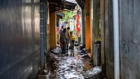 Warga membersihkan jalan dari sisa lumpur pascabanjir. 