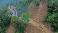 Foto udara petugas menggunakan alat berat membersihkan material longsor di Jalan Nasional III, Lumajang, Jawa Timur, Minggu (24/11/2024). 
