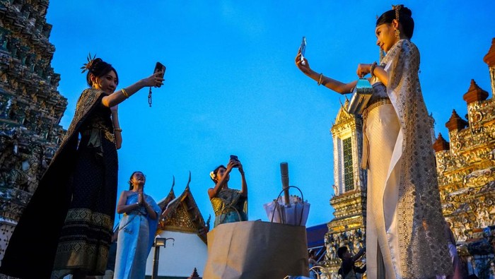 Wat Arun di Bangkok memukau wisatawan dengan pagoda porselen yang bersinar di malam hari. Kuil ini menjadi spot foto malam yang populer di kalangan wisatawan.