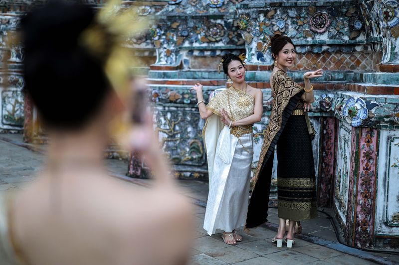 Wat Arun di Bangkok memukau wisatawan dengan pagoda porselen yang bersinar di malam hari. Kuil ini menjadi spot foto malam yang populer di kalangan wisatawan.