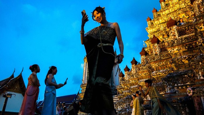 Wat Arun di Bangkok memukau wisatawan dengan pagoda porselen yang bersinar di malam hari. Kuil ini menjadi spot foto malam yang populer di kalangan wisatawan.