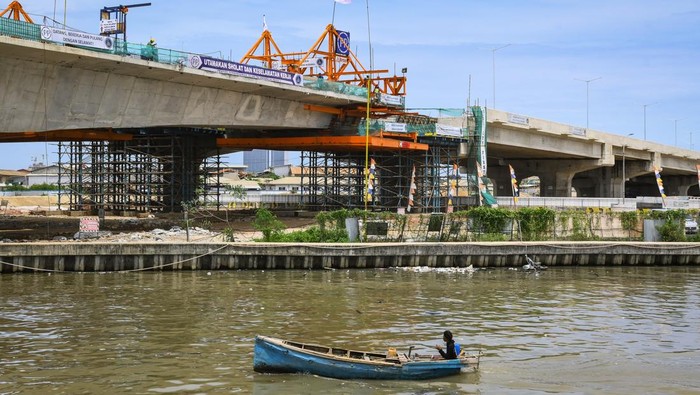 Nelayan melintas menggunakan perahu di dekat proyek pembangunan Jalan Tol Kamal-Teluknaga-Rajeg atau Tol PIK 2 di Kosambi, Kabupaten Tangerang, Banten, Minggu (24/11/2024). Jalan tol yang menghubungkan Tol Sedyatmo dan kawasan Pantai Indah Kapuk (PIK) 2 sepanjang 38,60 kilometer dengan anggaran Rp23 triliun tersebut direncanakan beroperasi pada Kuartal I/2025. ANTARA FOTO/Sulthony Hasanuddin/agr