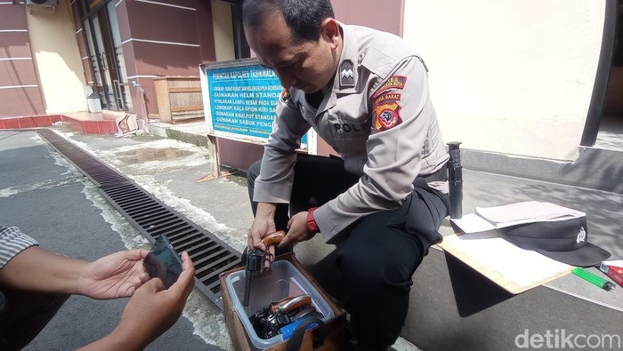 Polisi membereskan senjata api yang diamankan sementara dari petugas keamanan TPS.