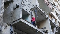 Seorang warga mengecek rumahnya yang rusak dirudal Israel. 