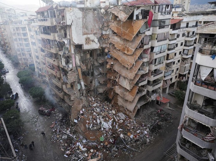 A woman uses her mobile phone as she stands near damaged buildings, in the aftermath of Israeli strikes on Beiruts southern suburbs, amid the ongoing hostilities between Hezbollah and Israeli forces, Lebanon November 25, 2024. REUTERS/Mohammed Yassin