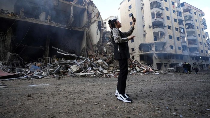 Potret Kawasan di Beirut Hancur Diserang Israel A woman uses her mobile phone as she stands near damaged buildings, in the aftermath of Israeli strikes on Beirut's southern suburbs, amid the ongoing hostilities between Hezbollah and Israeli forces, Lebanon November 25, 2024. REUTERS/Mohammed Yassin