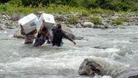 Personel kepolisian bersama petugas Bawaslu menyeberangi Sungai Tompobulu untuk mendistribusikan logistik Pilkada 2024 ke Dusun Makmur, Desa Bonto Manurung, Kecamatan Tompobulu, Kabupaten Maros, Sulawesi Selatan, Selasa (26/11/2024). 