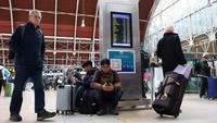 Penumpang kereta api menunggu dengan barang bawaan mereka setelah pembatalan kereta yang disebabkan oleh Badai Bert.  