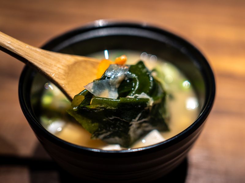 sup rumput laut A bowl of Japanese miso soup filled with kelp and ingredients.
