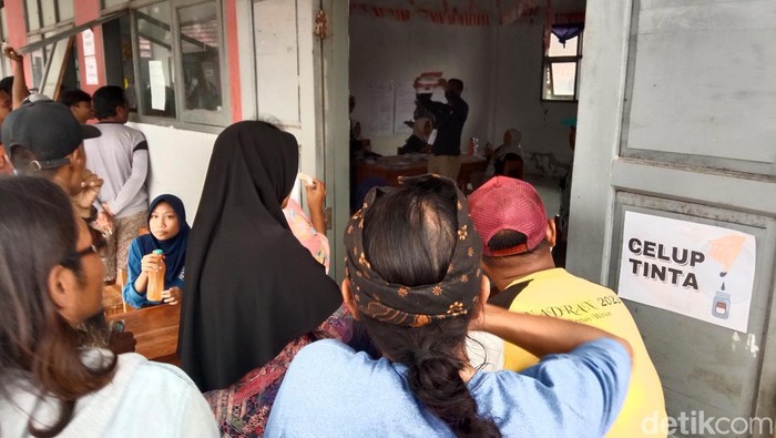 Antusias warga melihat proses penghitungan suara di tengah hujan lebat di Desa Eretan Wetan, Indramayu