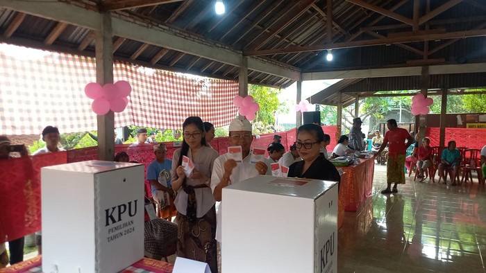 Cagub Bali nomor urut 2, Wayan Koster, mencoblos di TPS 1 Desa Sembiran, Kecamatan Tejakula, Buleleng, bersama istri dan anak bungsunya, Rabu (27/11/2024). (Wijaya Kusuma/detikBali)