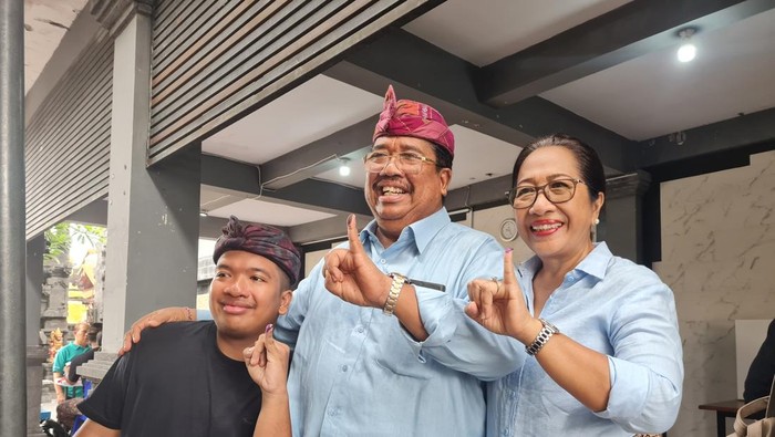 Cawagub nomor urut 1, Putu Agus Suradnyana (PAS) bersama sang istri, I Gusti Ayu Aries Sujati, dan anaknya menunjukkan jari kelingking berisi tinta seusai mencoblos di TPS 9, Banjar Bumi Shanti, Dauh Puri Kelod, Denpasar, Rabu (27/11/2024). (Vincencia Januaria Molo/detikBali)