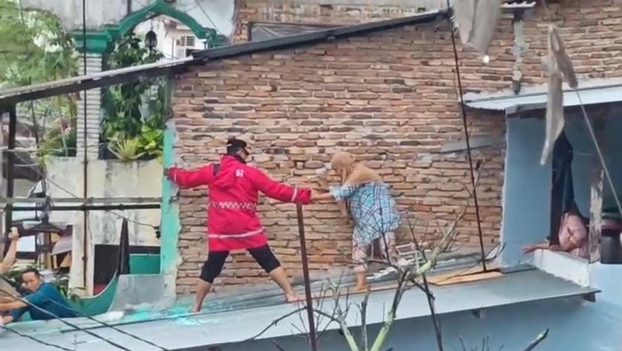 Kapolrestabes Medan Kombes Gidion Arif Setyawan (jas hujan merah) saat mengevakuasi nenek. Foto: Istimewa