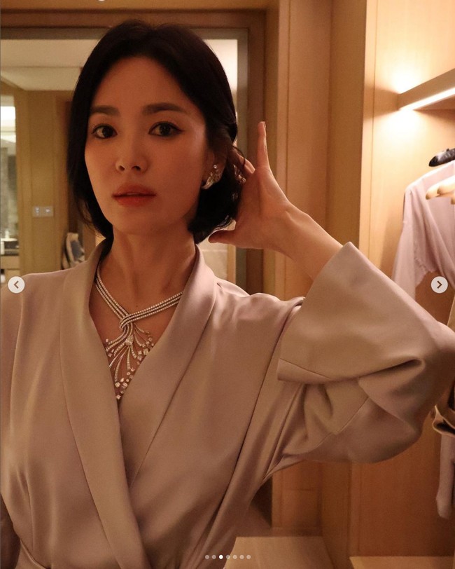 Song Hye Kyo tampil mengenakan celana dan coat satin warna abu-abu dari brand Korea, avouavou, saat hadir di acara Chaumet di Thailand. Yang menarik atensi dari gayanya ini adalah kalung besar yang menghiasi lehernya. Foto: Dok. Instagram Song Hye Kyo