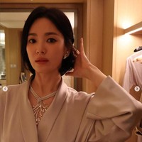 Song Hye Kyo tampil mengenakan celana dan coat satin warna abu-abu dari brand Korea, avouavou, saat hadir di acara Chaumet di Thailand. Yang menarik atensi dari gayanya ini adalah kalung besar yang menghiasi lehernya. Foto: Dok. Instagram Song Hye Kyo