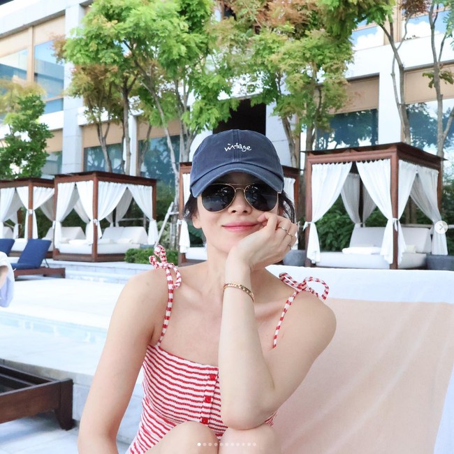 Setelah tampil glamour di acara Chaumet, Song Hye Kyo memamerkan gayanya bersantai di pinggir kolam renang di Thailand. Dia mengenakan baju renang merah garis-garis dan topi berwarna biru. Foto: Dok. Instagram Song Hye Kyo