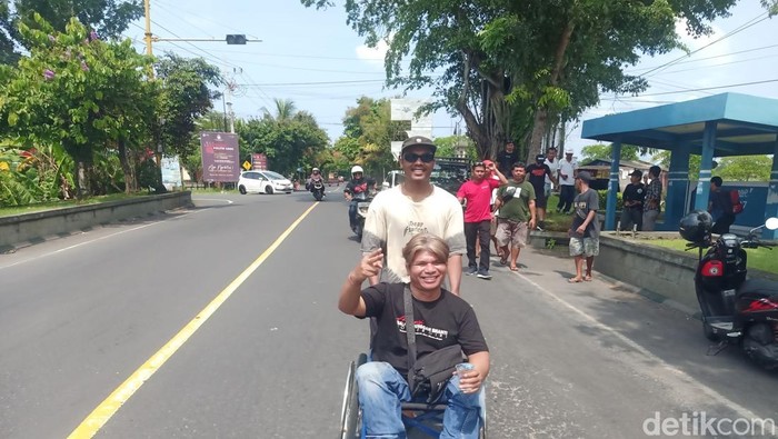 Komang Buda Ardita (48) menggunakan kursi roda sejauh lebih dari 20 kilometer menuju kantor DPC PDIP Jembrana, Kamis (28/11/2024). (I Putu Adi Budiastrawan/detikBali).