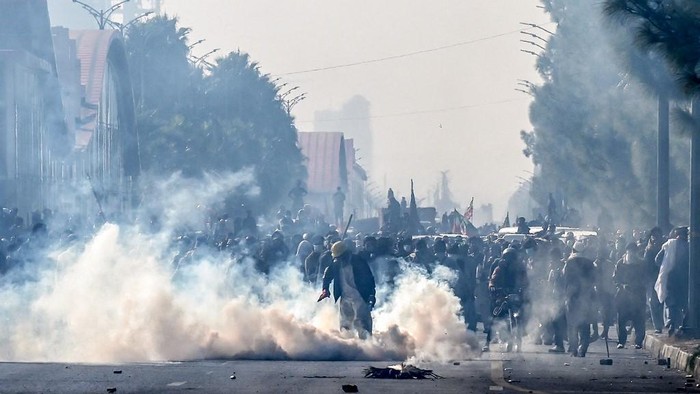 Policemen fire tear gas shells to disperse supporters of the Pakistan Tehreek-e-Insaf (PTI) party during a protest demanding the release of former prime minister Imran Khan, at the Red Zone area in Islamabad on November 26, 2024. Pakistani protesters demanding the release of ex-prime minister Imran Khan on November 26 killed four members of the nations security forces, the government said, as the crowds defied police and closed in on the capitals centre. (Photo by Aamir QURESHI / AFP)