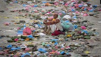 Seorang pendeta duduk di tengah sampah yang ditinggalkan umat selama Kuse Aunsi di Kuil Gokarneshwor di Kathmandu. Foto: AP/Niranjan Shrestha