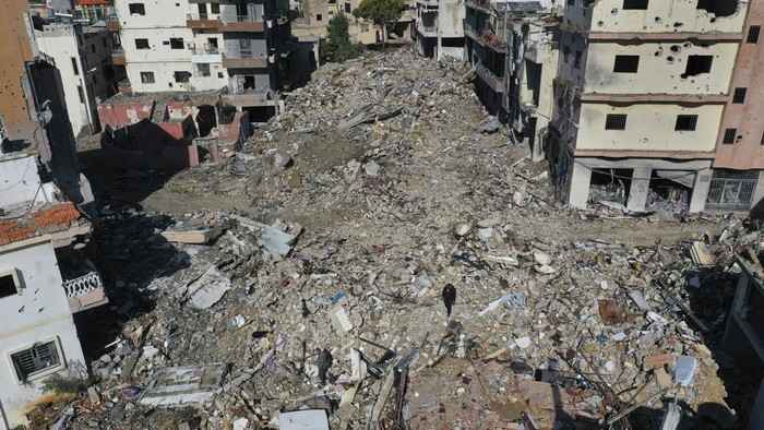 Residents walk on the rubble of destroyed buildings after they returned to Qana village, southern Lebanon, Thursday, Nov. 28, 2024 following a ceasefire between Israel and Hezbollah that went into effect on Wednesday.(AP Photo/Hussein Malla)